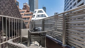 A balcony with wicker furniture and a view of surrounding buildings. - SeRENO Shinmachi 801 (Osaka)