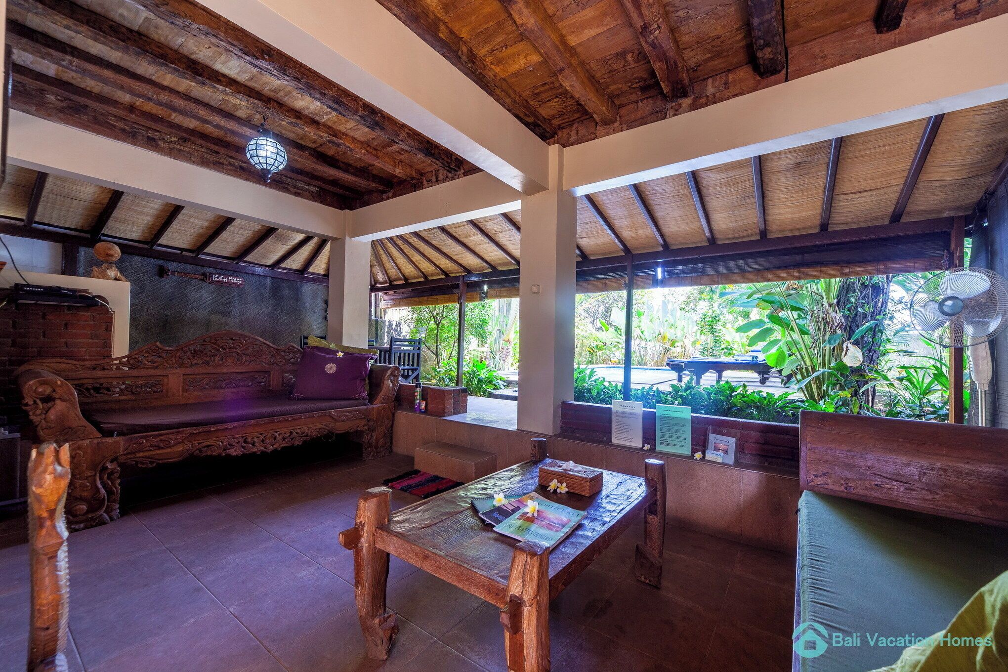 A wooden interior with a sofa, a table, and a fan.
