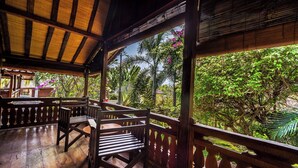 A wooden deck with a railing, a table, and two chairs. - Villa Seahorse, Bali - Lovina Beach Poolvilla, 2BR Joglo! (Buleleng)