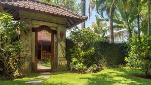 A stone structure with a tiled roof, a wooden door, and a pathway leading to a covered area. - Villa Seahorse, Bali - Lovina Beach Poolvilla, 2BR Joglo! (Buleleng)