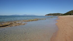 A beach with clear shallow waters, a sandy shore, and distant mountains. - King tent 5 Nelly bay (Nelly Bay)