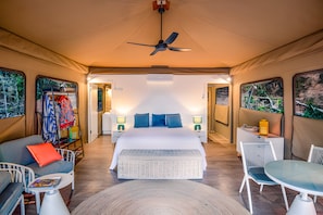 A tented accommodation with a bed, seating area, and a table. - King tent 5 Nelly bay (Nelly Bay)