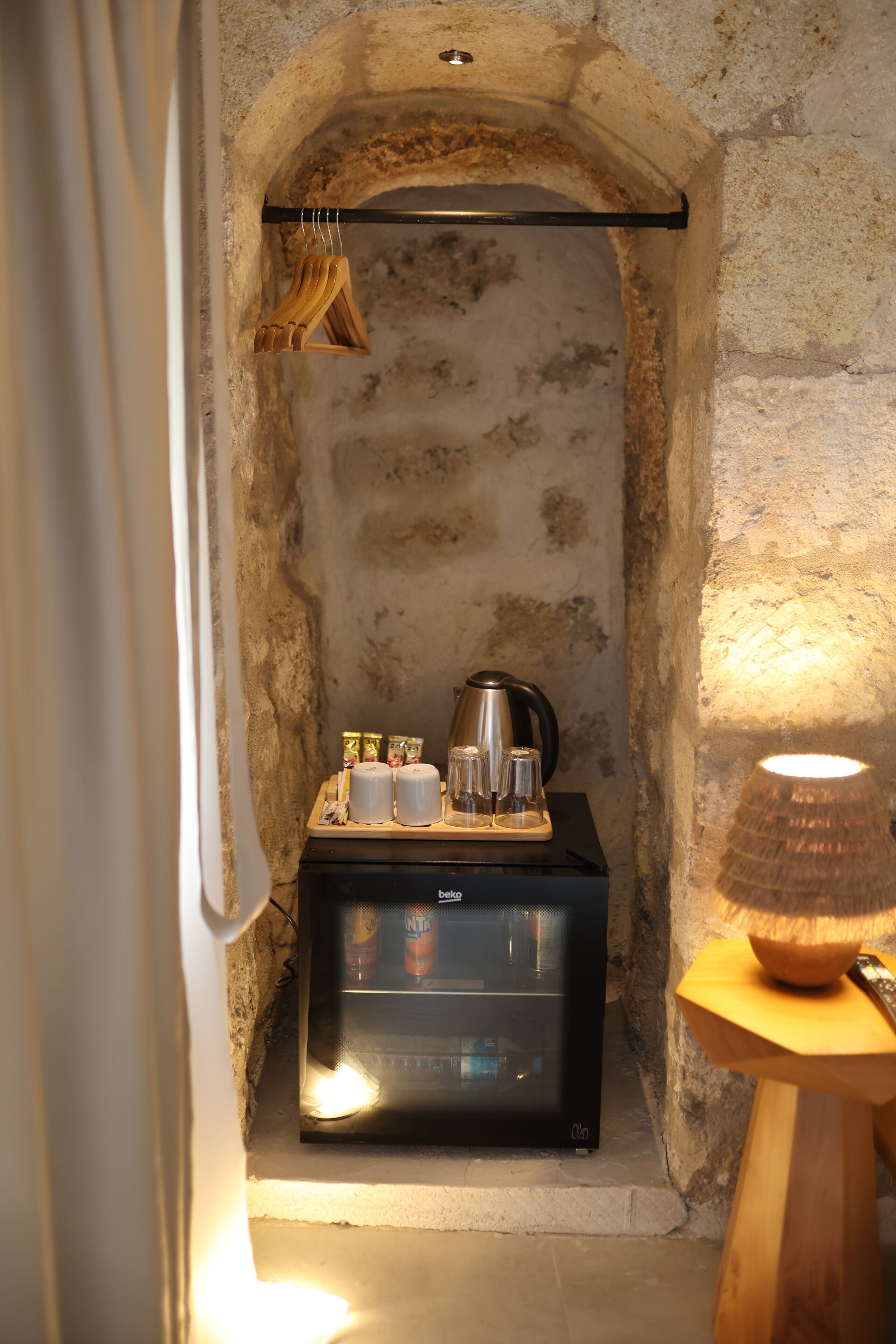 A compact kitchenette with a coffee machine, tea set, and a lamp.