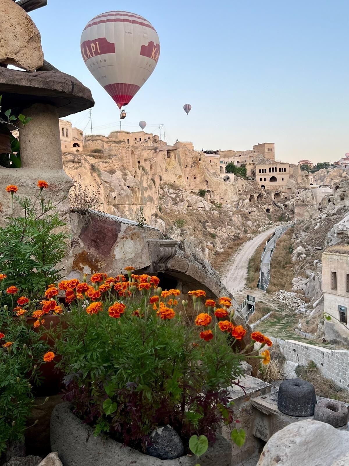 Un puente de piedra histórico con un jardín de flores al frente y vistas de edificios antiguos al fondo.