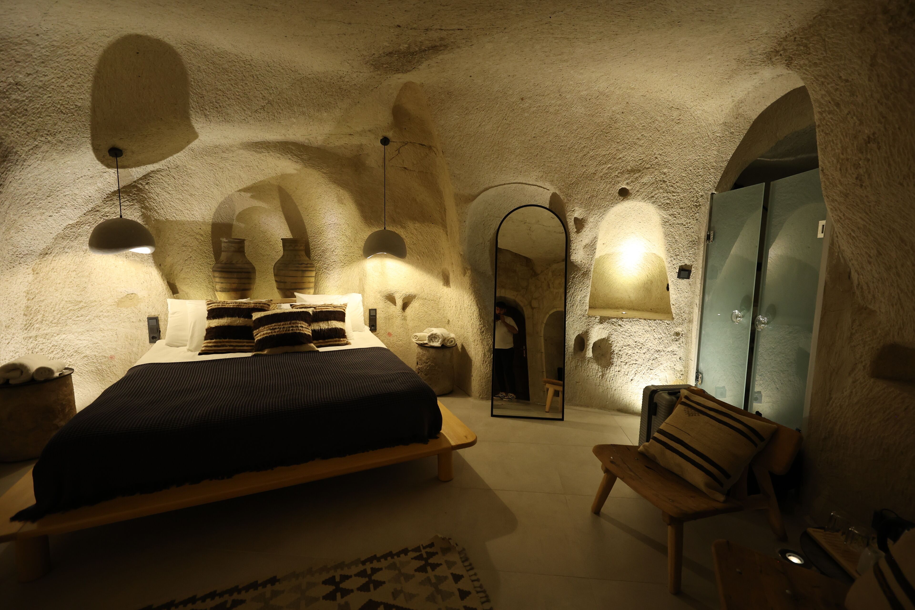 Une chambre à coucher avec un lit, un banc, un miroir et une armoire.