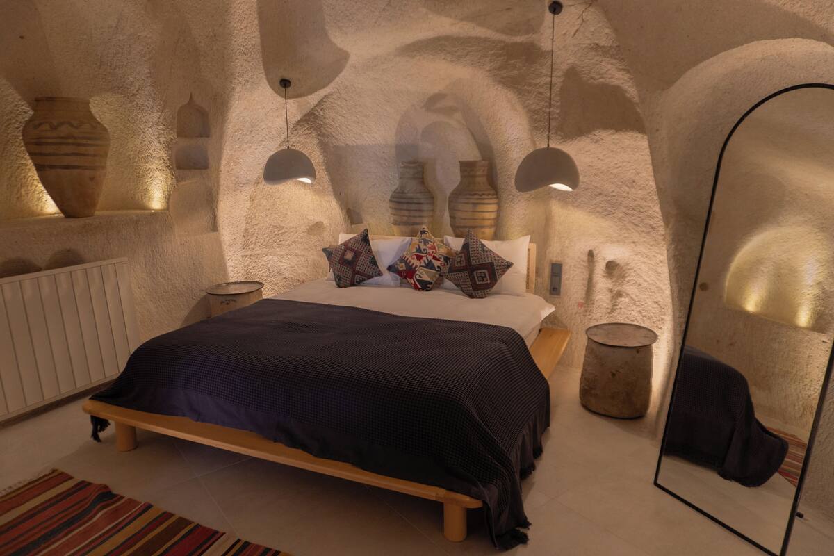 Une chambre à coucher avec un lit, des oreillers, un miroir et des vases décoratifs accrochés aux murs.