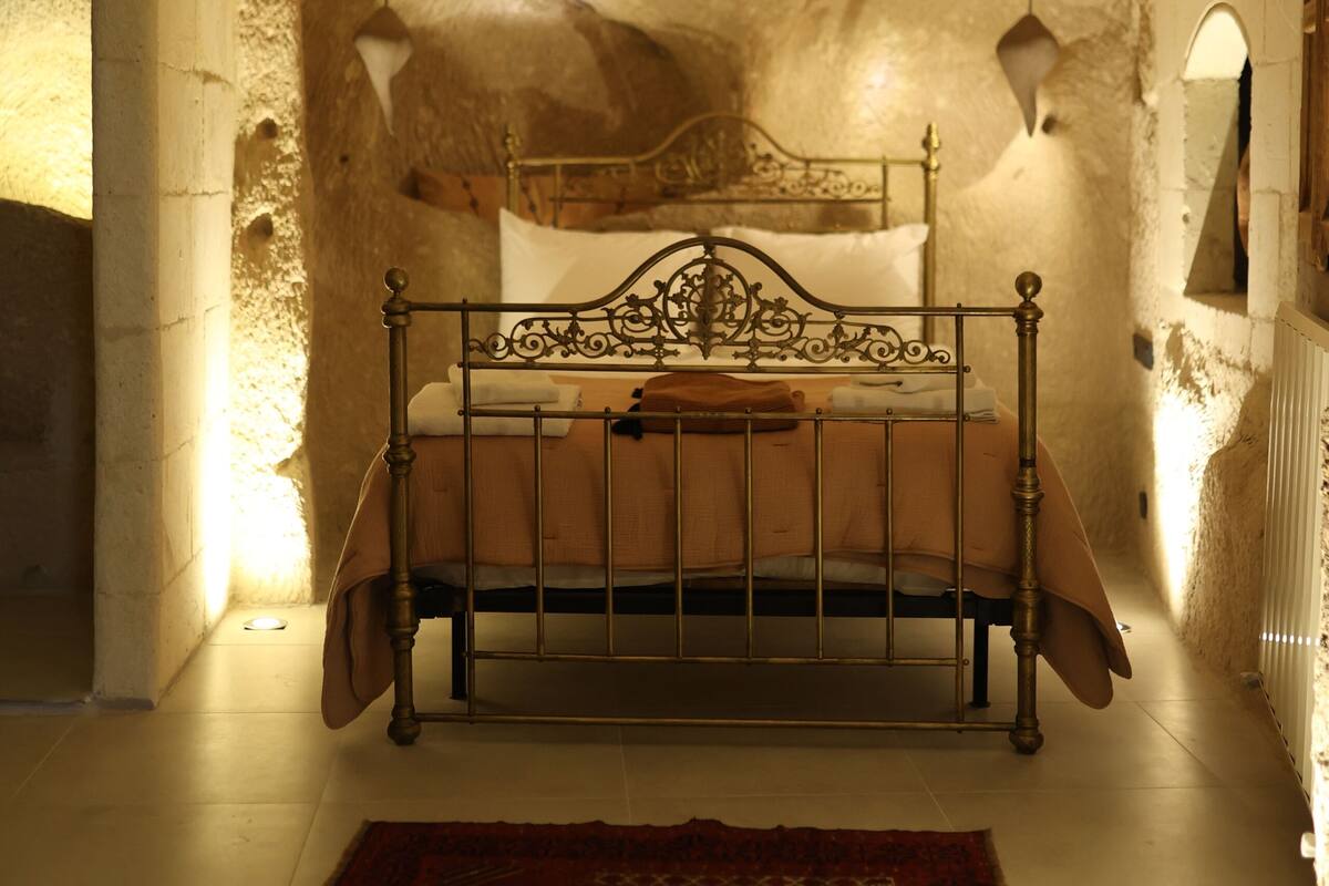 Une chambre à coucher avec un lit, un plafond avec des poutres en bois et un tapis à motifs.