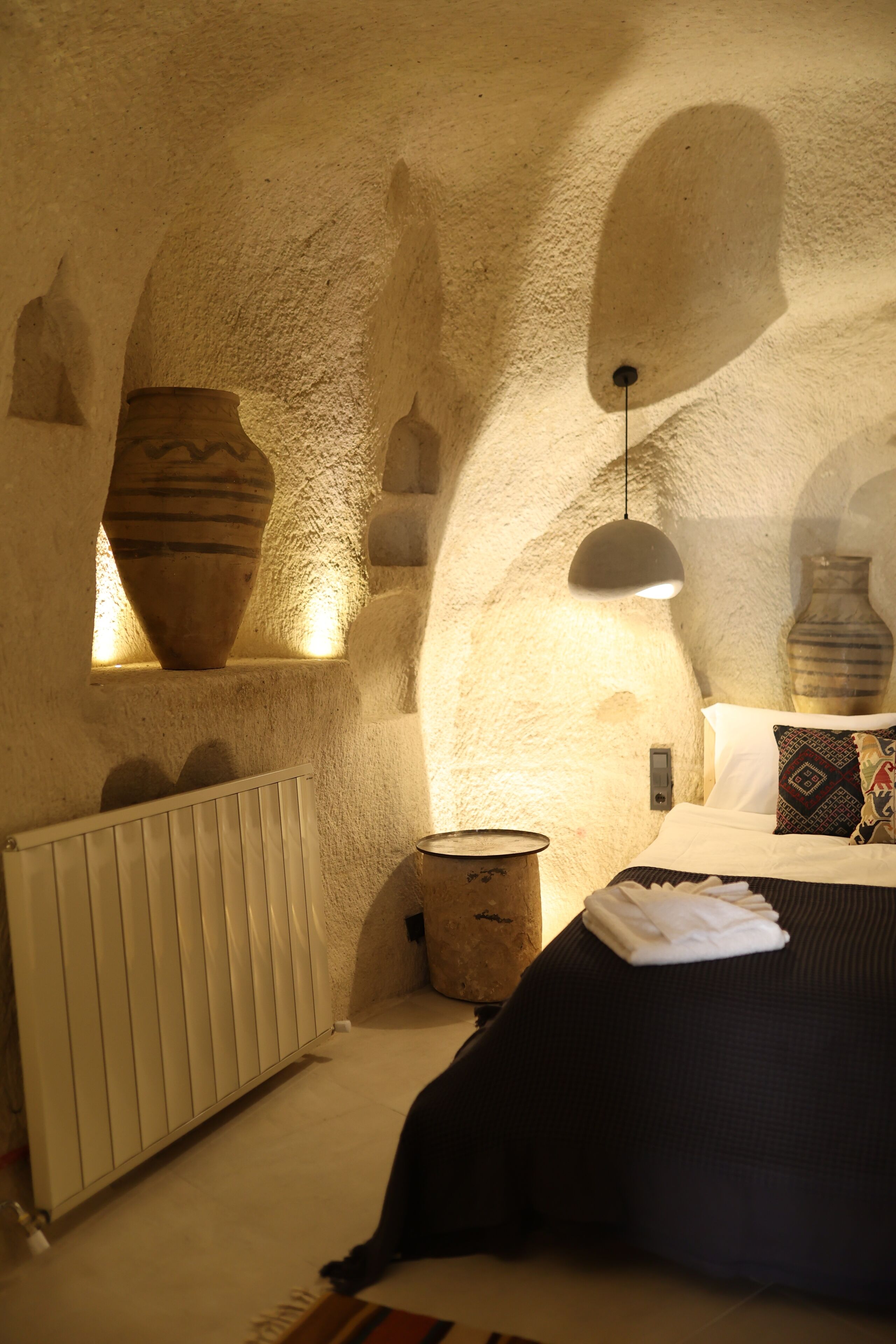 A cozy room with a bed, a radiator, and a hanging light fixture.