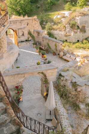 Un patio de piedra con escaleras, asientos exteriores y plantas en macetas.