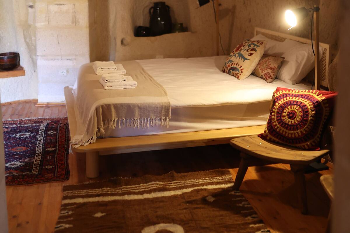 Une chambre à coucher chaleureuse et rustique, avec un lit, une lampe de chevet et une chaise en bois.
