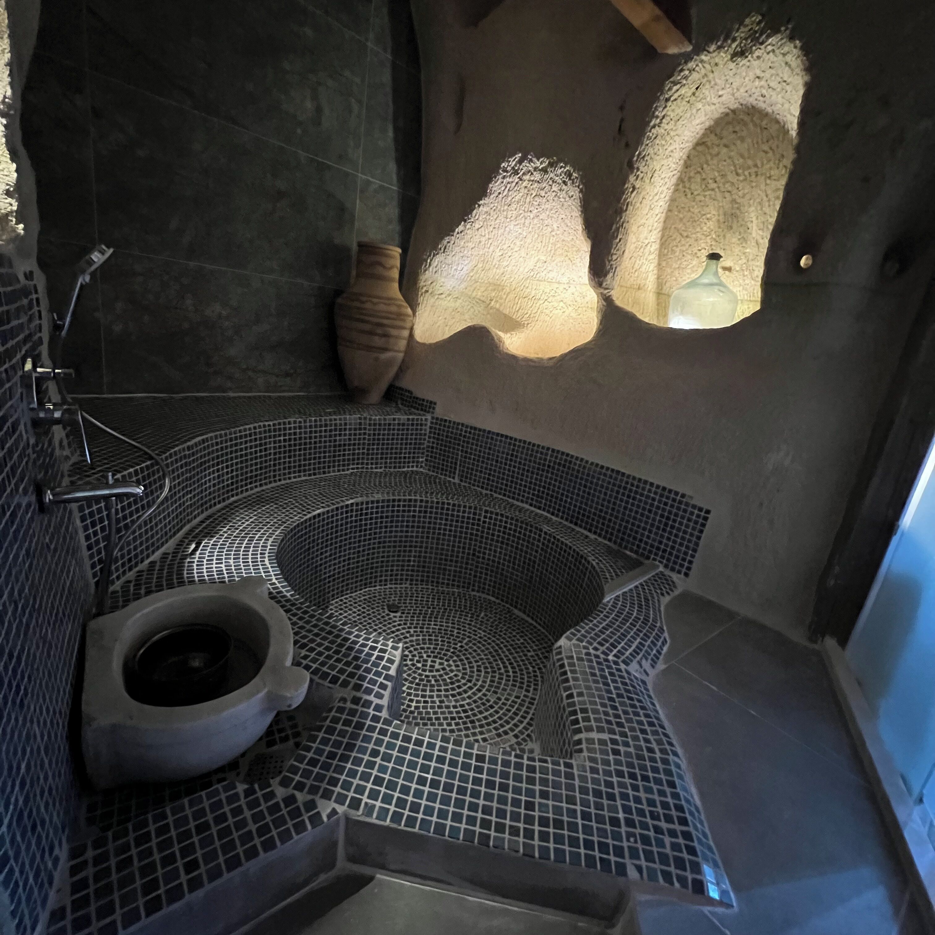 A bathroom with a large, circular hot tub, a toilet, and a shower area.