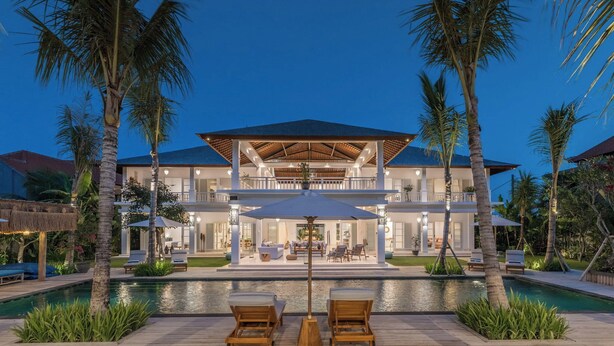 A modern two-story house with a pool, surrounded by palm trees.