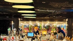 Zona de bar con taburetes, una barra y un cantinero.