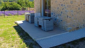 A stone building with a patio, outdoor seating, and a view of lavender fields.