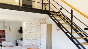 A modern living room with a sofa, a wooden coffee table, and a staircase with a wooden handrail.