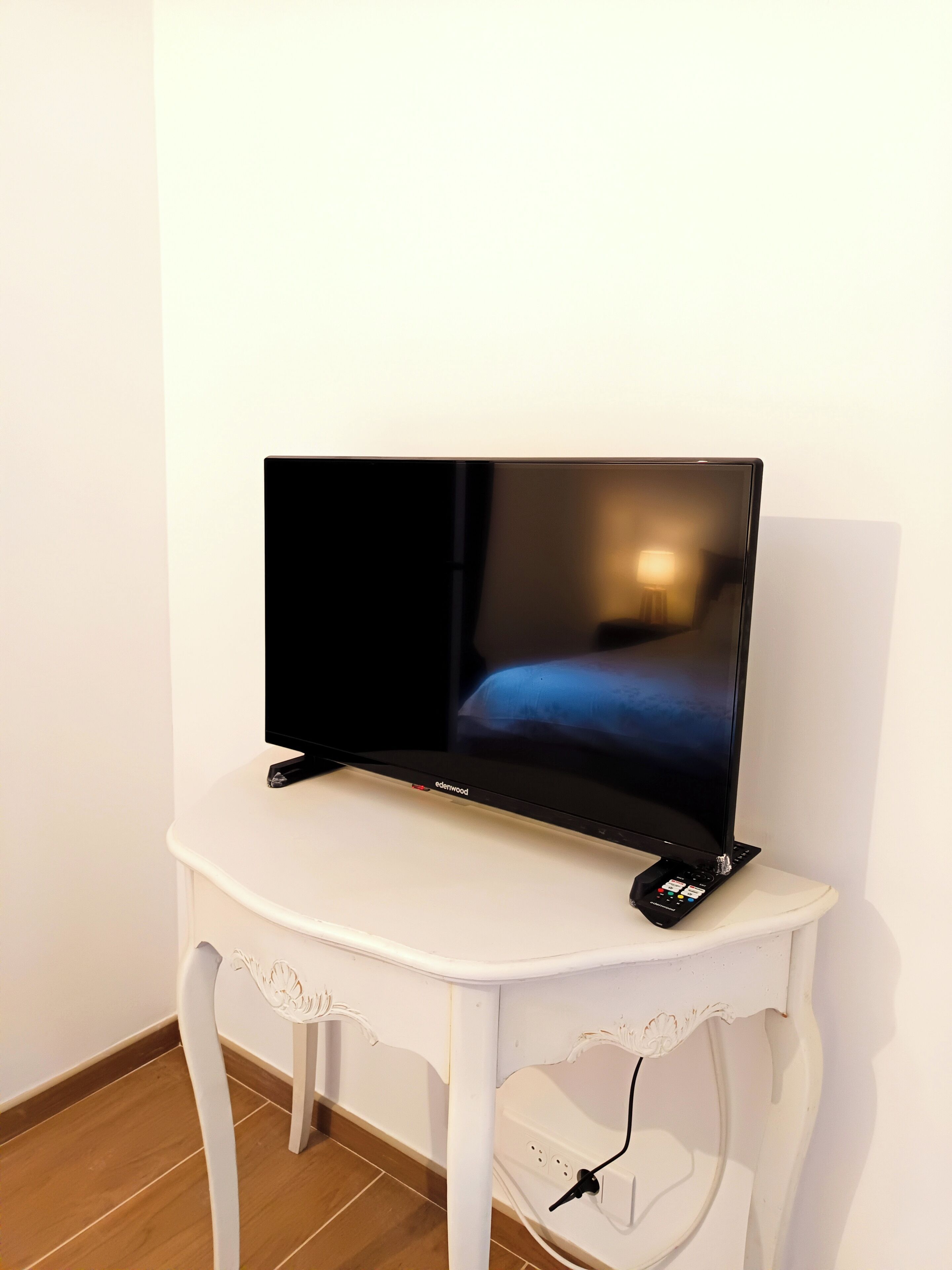 Ein Flachbildfernseher auf einem weißen Tisch, mit eingestecktem Stromkabel.