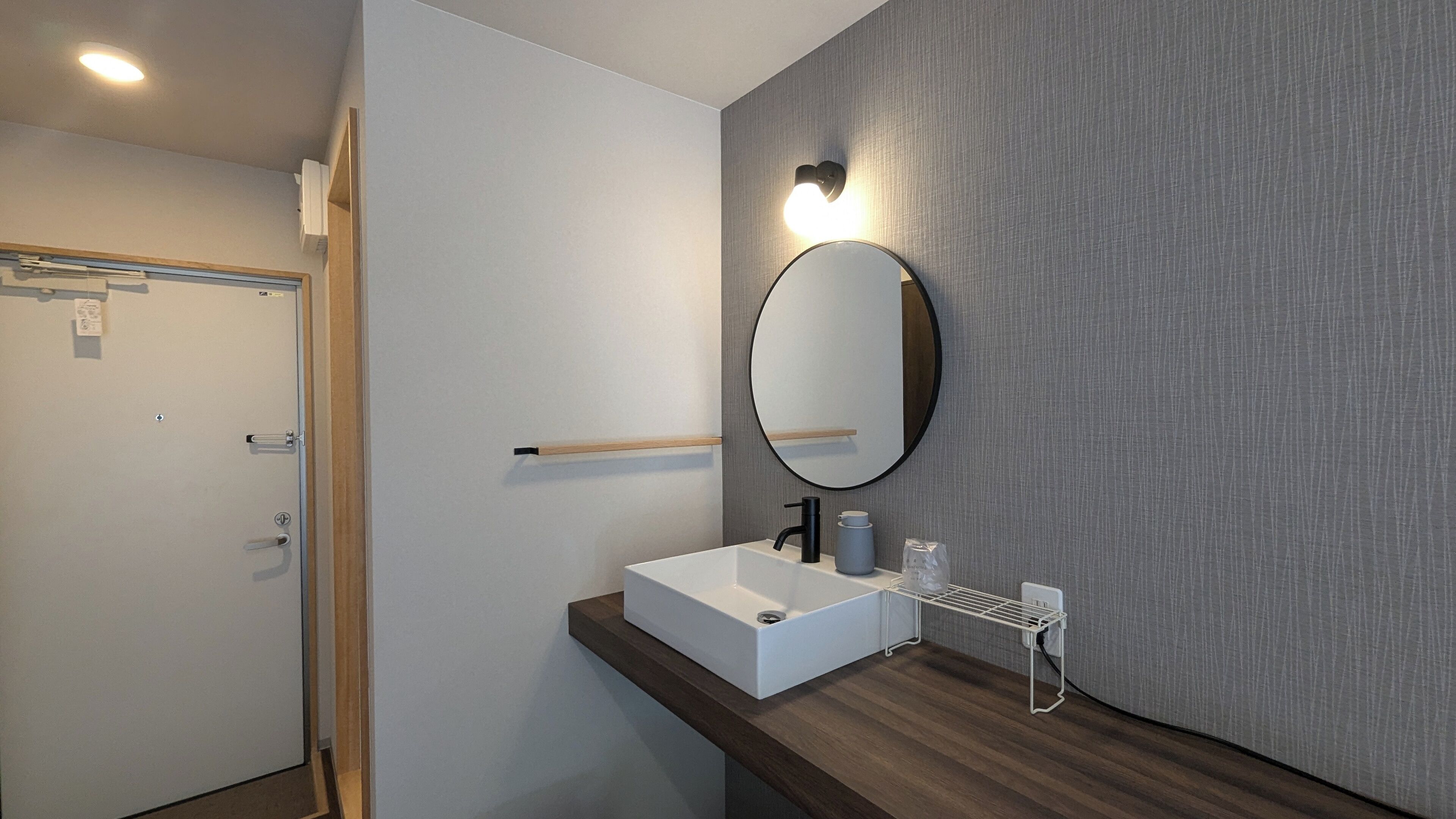 A modern bathroom with a white sink, a round mirror, and a towel rack.
