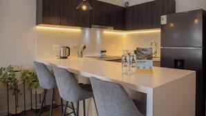 Eine moderne Küche mit dunklen Holzschränken, einer weißen Arbeitsplatte und zwei Barhocker.