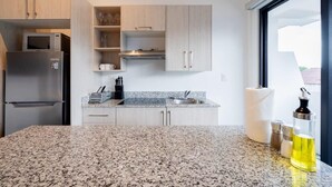 Una cocina moderna con encimeras de granito, electrodomésticos de acero inoxidable y armarios de madera clara.
