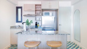 Une cuisine moderne dotée d’un îlot central, d’appareils électroménagers en acier inoxydable, de meubles en bois et d’un sol à motifs.