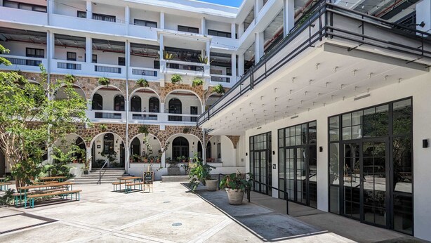 Une cour dotée d’une façade en pierre, de nombreux balcons et d’un espace aménagé pour s’asseoir à l’extérieur.