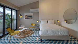 A hotel room with a large bed, a round mirror, and a dining area with yellow chairs and a small table. - w* | Comfortable Loft in Santa Ana (Panamá)