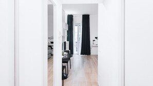 Une pièce moderne et minimaliste, dotée d’un plancher en bois, d’un coin repas avec une table et des chaises, et offrant une vue sur l’extérieur grâce à une porte vitrée.