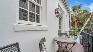 Ein weißes Gebäude mit einem Balkon, einem Tisch und Stühlen.
