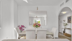 Une chambre d’hôtel moderne, dotée d’un grand lit, d’un bureau avec une chaise, d’un miroir et d’un vase avec des fleurs.