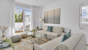 Un salon moderne avec un canapé, une table basse et une grande fenêtre donnant sur l’extérieur.
