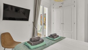 Une chambre à coucher avec un lit, un téléviseur fixé au mur et une porte donnant sur un balcon.