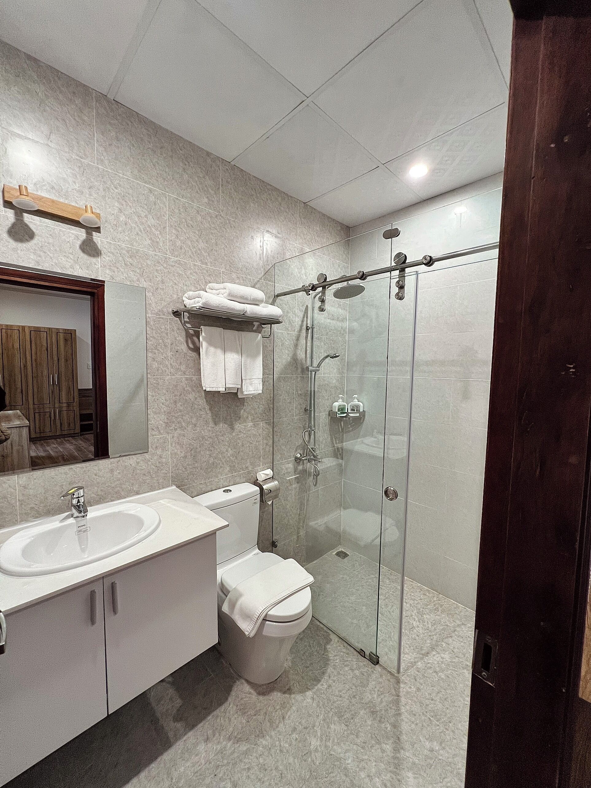 Une salle de bain moderne avec une douche à parois de verre, un lavabo blanc et des toilettes.