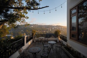Eine Terrasse mit Sitzgelegenheiten im Freien, Blick auf eine Stadtlandschaft und Lichterketten.