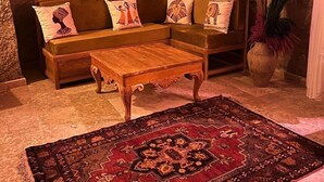 A cozy living room with a sectional sofa, a wooden coffee table, and a patterned rug. - Songül Hanım Konağı (Ürgüp)
