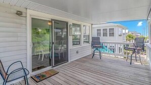 A covered porch with a sliding glass door, a wooden deck, and two chairs. - 3 Blocks to Beach + FREE Golf Cart | Sleeps 10 (North Myrtle Beach)