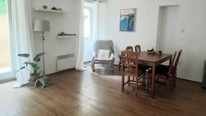 En matplats med ett träbord och stolar, en lampa, ett element och ett fönster med gardiner.