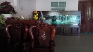 A room with a wooden chair, a fish tank, and a decorative statue. - Gia Tu Hotel (Bien Hoa)