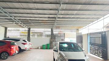 A covered parking area with cars parked under a corrugated metal roof.