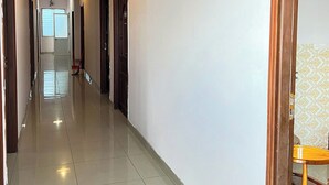 A long, narrow hallway with a tiled floor, wooden doors, and a bright ceiling light. - Gia Tu Hotel (Bien Hoa)
