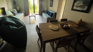 Un salon moderne avec une table à manger en bois, un canapé et une grande fenêtre agrémentée de rideaux.