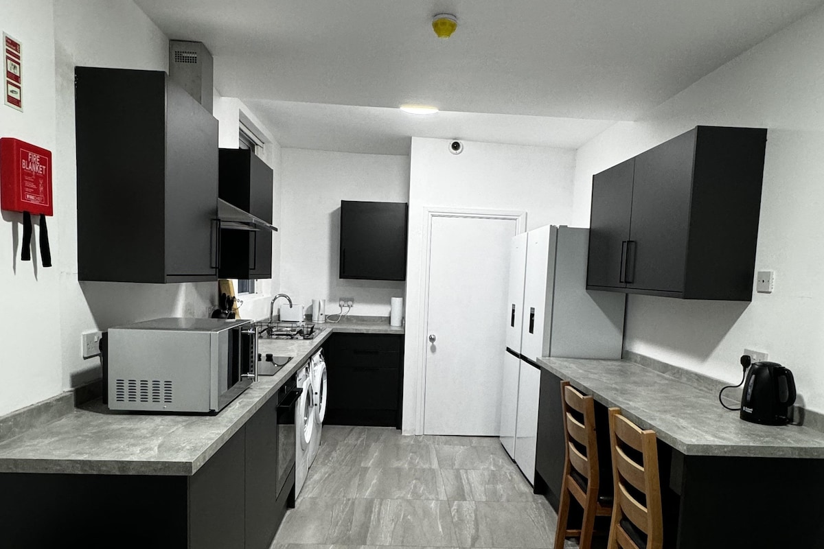 A modern kitchen with black cabinets, a microwave, a coffee maker, and a dishwasher.