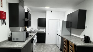 Una cucina moderna con mobili neri, un forno a microonde, una macchina da caffè e una lavastoviglie.
