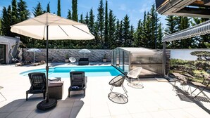 En trädgård med en pool, solstolar och en pergola.