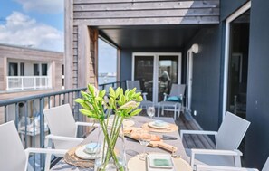 Enjoy a casual meal on the balcony with a glass table and comfortable seating.