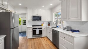 A modern kitchen with white cabinetry, stainless steel appliances, and a wooden floor. - Renovated Capital Heights Home (Baton Rouge)