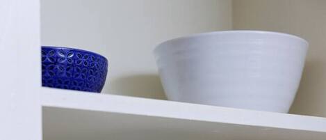 A white shelf with stacked white bowls and a single blue bowl.