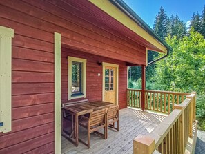 A wooden cabin with a porch, a table, and chairs.
