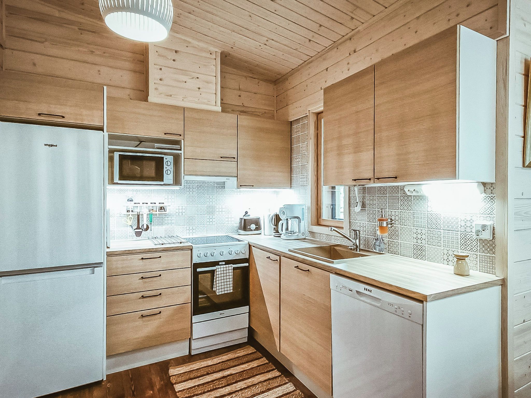 A compact kitchen with wooden cabinets, a microwave, a stove, and a dishwasher.