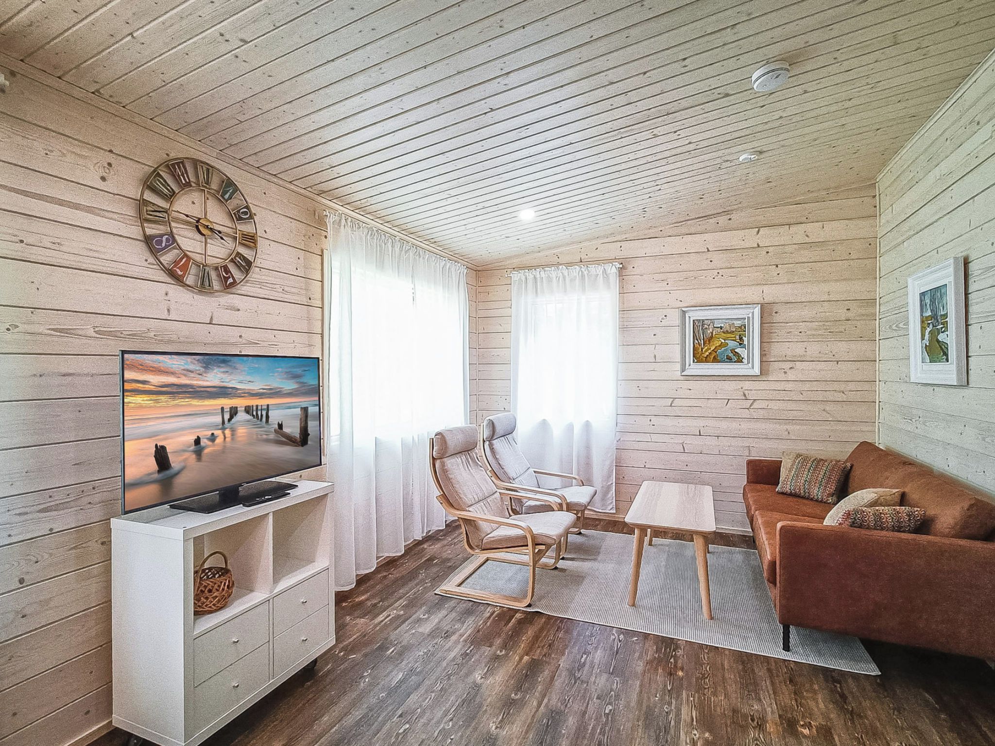 Una sala de estar acogedora con techo de madera, televisor, sofá, mesa de centro y dos sillones.