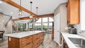 Cocina moderna con armarios de madera, una isla grande e iluminación colgante.
